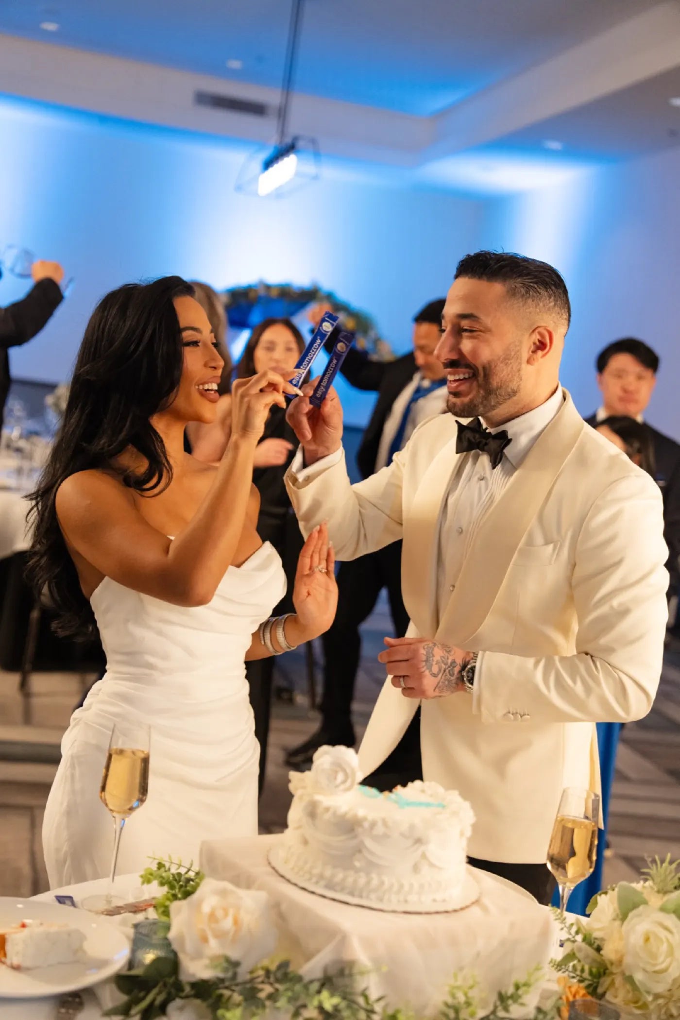 Bride and groom laughing at the cake table with an Easy Tomorrow stick