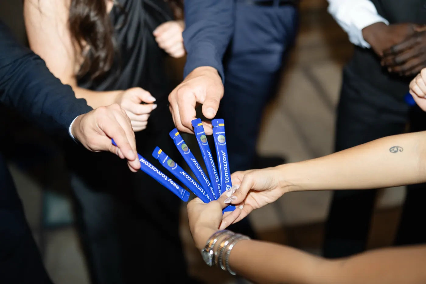 Guests reaching in to grab Easy Tomorrow sticks together on the dance floor