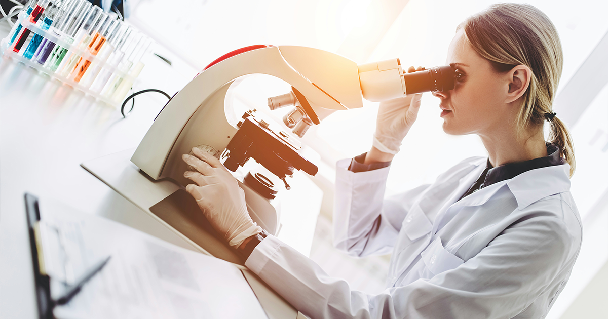 Scientist looking through a microscope in a lab.