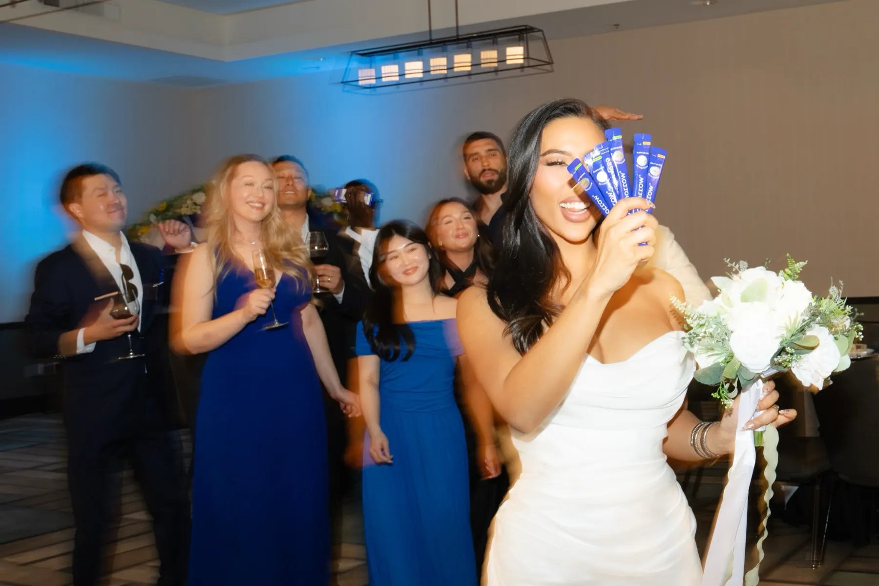 Bride laughing with her wedding party, bouquet in hand
