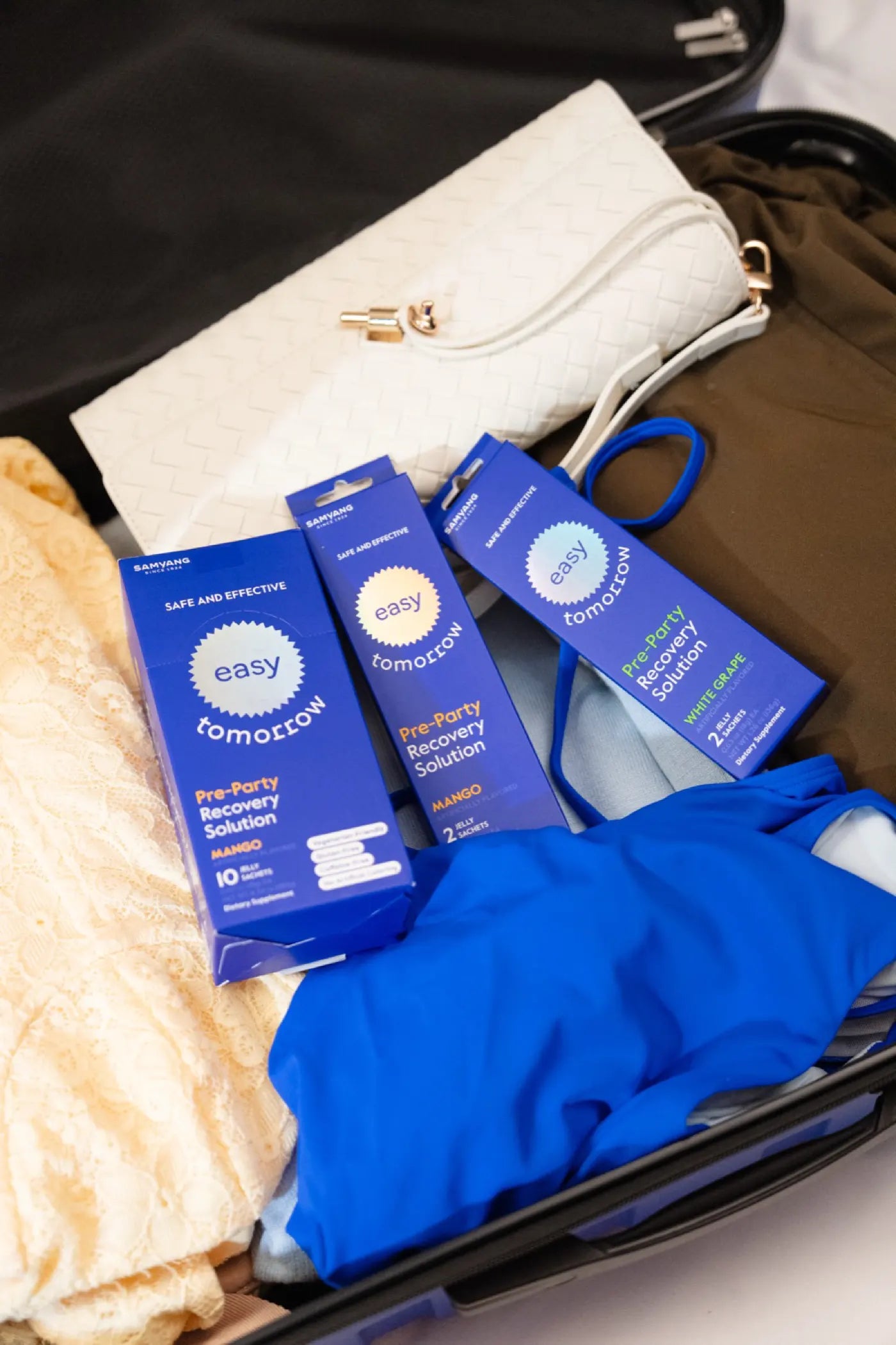 Open suitcase packed with Easy Tomorrow boxes among travel outfits